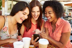 Tres amigos femeninos que leen el mensaje de texto en el ½ de CafÅ imagen de archivo Tres amigos femeninos que leen el mensaje de texto en el ½ de CafÅ imagen de archivo