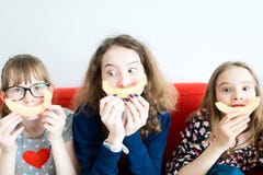 Tres chicas jóvenes que se sientan en el sofá rojo y que comen el melón amarillo libre illustration Tres chicas jóvenes que se sientan en el sofá rojo y que comen el melón amarillo libre illustration