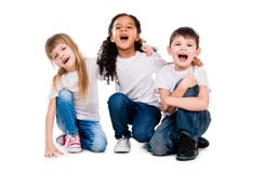 Tres niños de moda divertidos ríen sentarse en el piso imágenes de archivo libres de regalías Tres niños de moda divertidos ríen sentarse en el piso imágenes de archivo libres de regalías