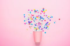 Trinkende Papierschale mit den mehrfarbigen Konfettis zerstreut auf pinkfarbenen Hintergrund Flache Lagezusammensetzung süße Kuch stockbild Trinkende Papierschale mit den mehrfarbigen Konfettis zerstreut auf pinkfarbenen Hintergrund Flache Lagezusammensetzung süße Kuch stockbild