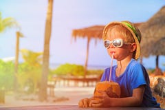 Trinkendes Kokosnusscocktail des kleinen Jungen auf Strand stockbild Trinkendes Kokosnusscocktail des kleinen Jungen auf Strand stockbild