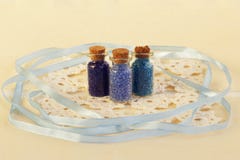Trois bouteilles en verre minuscules avec du liège bouchent, rempli de couleurs bleues des perles, de la serviette et du ruban bl photographie stock Trois bouteilles en verre minuscules avec du liège bouchent, rempli de couleurs bleues des perles, de la serviette et du ruban bl photographie stock