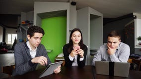 Trois collègues, femelle et deux jeunes hommes s'asseyent dans le réseau social images libres de droits Trois collègues, femelle et deux jeunes hommes s'asseyent dans le réseau social images libres de droits