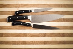 Trois couteaux de cuisine au-dessus de la planche à découper en bambou Images stock Trois couteaux de cuisine au-dessus de la planche à découper en bambou Images stock