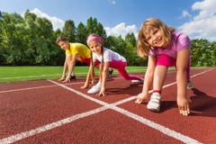 Trois enfants de sourire en position prête à courir photo stock Trois enfants de sourire en position prête à courir photo stock