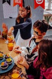 Trois enfants mangeant des petits gâteaux tout en ayant la partie de Halloween dans le jardin d'enfants photographie stock libre de droits Trois enfants mangeant des petits gâteaux tout en ayant la partie de Halloween dans le jardin d'enfants photographie stock libre de droits
