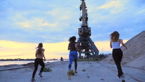 Trois femmes sportives dans des survêtements pulsent le long du pilier de sable du port de cargaison, au crépuscule du matin clips vidéos Trois femmes sportives dans des survêtements pulsent le long du pilier de sable du port de cargaison, au crépuscule du matin clips vidéos