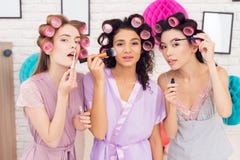 Trois filles avec des bigoudis dans leur faire de cheveux composent Ils célèbrent des femmes ` s jour le 8 mars Photos stock Trois filles avec des bigoudis dans leur faire de cheveux composent Ils célèbrent des femmes ` s jour le 8 mars Photos stock
