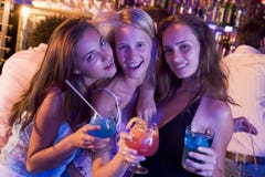 Trois jeunes femmes avec des boissons dans une boîte de nuit photographie stock Trois jeunes femmes avec des boissons dans une boîte de nuit photographie stock