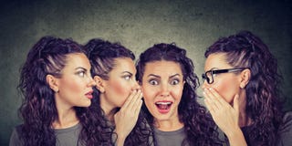 Trois jeunes femmes se chuchotant et à une fille étonnée choquée photos stock Trois jeunes femmes se chuchotant et à une fille étonnée choquée photos stock