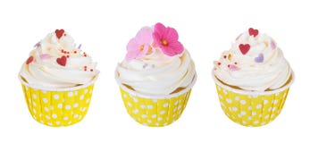 Trois petits gâteaux crèmes de beurre avec les fleurs douces et coeurs dans la tasse de papier de point de polka d'isolement sur Photographie stock libre de droits Trois petits gâteaux crèmes de beurre avec les fleurs douces et coeurs dans la tasse de papier de point de polka d'isolement sur Photographie stock libre de droits