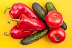 Trois poivrons rouges lumineux, trois concombres verts et deux tomates rouges sur la fin jaune de vue supérieure de fond photographie stock Trois poivrons rouges lumineux, trois concombres verts et deux tomates rouges sur la fin jaune de vue supérieure de fond photographie stock