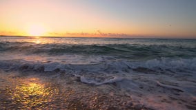 Tropical sunrise over the beach. Sea waves washing the sand
