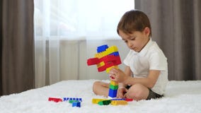 Troszkę siedzi w pokoju na łóżku i sztukach z meccano chłopiec zbiory wideo Troszkę siedzi w pokoju na łóżku i sztukach z meccano chłopiec zbiory wideo