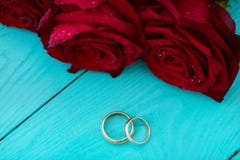Trouwringen en rode rozen Huwelijksboeket op blauwe houten achtergrond Selectieve nadruk De ruimte van het exemplaar Spot omhoog royalty-vrije stock afbeelding Trouwringen en rode rozen Huwelijksboeket op blauwe houten achtergrond Selectieve nadruk De ruimte van het exemplaar Spot omhoog royalty-vrije stock afbeelding
