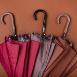 Trzy barwioni parasole przechujący w brown tle obraz stock Trzy barwioni parasole przechujący w brown tle obraz stock