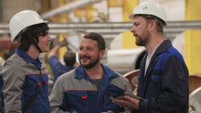 Trzy przyjaciela inżyniera w przemysł ciężki fabryce, uśmiech i dyskutują plany zbiory wideo Trzy przyjaciela inżyniera w przemysł ciężki fabryce, uśmiech i dyskutują plany zbiory wideo