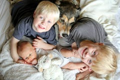 Trzy Szczęśliwego młodego dziecka Snuggling z zwierzę domowe psem w łóżku zdjęcie royalty free Trzy Szczęśliwego młodego dziecka Snuggling z zwierzę domowe psem w łóżku zdjęcie royalty free
