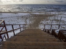 Trämoment - ner till den sandiga stranden i Östersjön på en molnig dag för vinter på solnedgången i Klaipeda, Litauen royaltyfri foto Trämoment - ner till den sandiga stranden i Östersjön på en molnig dag för vinter på solnedgången i Klaipeda, Litauen royaltyfri foto