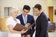 Três consultantes que discutem notas pacientes no hospital fotos de stock royalty free Três consultantes que discutem notas pacientes no hospital fotos de stock royalty free