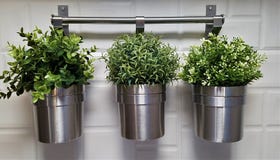 Três potenciômetros do metal com as plantas falsificadas verdes fotografia de stock Três potenciômetros do metal com as plantas falsificadas verdes fotografia de stock