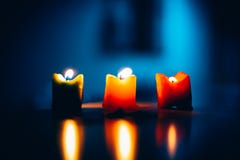 Três velas ardentes em seguido com fundo azul imagem de stock Três velas ardentes em seguido com fundo azul imagem de stock
