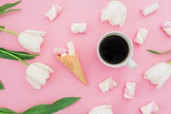 Tulips flowers with mug of coffee, marshmallows and waffle cone on pastel pink background. Blogger concept. Flat lay, top view. Stock Photos Tulips flowers with mug of coffee, marshmallows and waffle cone on pastel pink background. Blogger concept. Flat lay, top view. Stock Photos