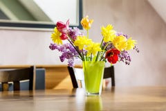 Tulips,narcissus and lilac flowers in a green glass vase on a wooden table royalty free stock images Tulips,narcissus and lilac flowers in a green glass vase on a wooden table royalty free stock images