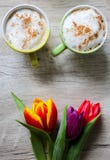 Tulpen op houten achtergrond met twee koppen van koffie Uitnodigingsprentbriefkaar voor de dag van de moeder of de dag van intern royalty-vrije stock afbeelding Tulpen op houten achtergrond met twee koppen van koffie Uitnodigingsprentbriefkaar voor de dag van de moeder of de dag van intern royalty-vrije stock afbeelding