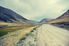 Tundra ερήμων κοιλάδα ποταμών υψηλών βουνών με το σκονισμένο δρόμο Στοκ Φωτογραφία Tundra ερήμων κοιλάδα ποταμών υψηλών βουνών με το σκονισμένο δρόμο Στοκ Φωτογραφία