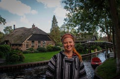 Turist för ung kvinna i etniska tröja- och bandanaställningar mot bakgrunden av den berömda byn av Githorn arkivbilder Turist för ung kvinna i etniska tröja- och bandanaställningar mot bakgrunden av den berömda byn av Githorn arkivbilder