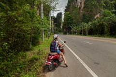 Turist- kvinnasammanträde på den klassiska sparkcykeln mot bakgrunden av bergen av det Krabi landskapet, Thailand royaltyfria bilder Turist- kvinnasammanträde på den klassiska sparkcykeln mot bakgrunden av bergen av det Krabi landskapet, Thailand royaltyfria bilder