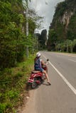 Turist- kvinnasammanträde på den klassiska sparkcykeln mot bakgrunden av bergen av det Krabi landskapet, Thailand royaltyfri fotografi Turist- kvinnasammanträde på den klassiska sparkcykeln mot bakgrunden av bergen av det Krabi landskapet, Thailand royaltyfri fotografi