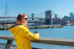Turista feliz de la mujer joven que hace turismo en New York City en el día de primavera soleado Café de consumición del viajero foto de archivo libre de regalías Turista feliz de la mujer joven que hace turismo en New York City en el día de primavera soleado Café de consumición del viajero foto de archivo libre de regalías