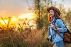 Turista femminile con lo zaino e macchina fotografica in campagna con il tramonto fotografia stock Turista femminile con lo zaino e macchina fotografica in campagna con il tramonto fotografia stock