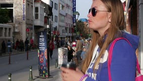 Turkiet Antalya, mars 2016: en flicka som dricker kaffe från en kopp på gatan lager videofilmer Turkiet Antalya, mars 2016: en flicka som dricker kaffe från en kopp på gatan lager videofilmer