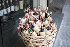 Tuscan wine. wicker basket displayed on the street in front of a vintage bottle shop. small flasks of local red wine for souvenirs stock images Tuscan wine. wicker basket displayed on the street in front of a vintage bottle shop. small flasks of local red wine for souvenirs stock images