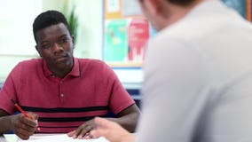 Tutor taxa de matrícula de Gives Male Student um a um da High School na mesa video estoque Tutor taxa de matrícula de Gives Male Student um a um da High School na mesa video estoque