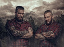 Två brutala grabbar med tatueringar på deras armar i berg royaltyfria bilder Två brutala grabbar med tatueringar på deras armar i berg royaltyfria bilder