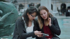 Två flickor läste en lopphandbok i centret av London lager videofilmer Två flickor läste en lopphandbok i centret av London lager videofilmer