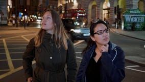 Två flickor på den Piccadilly cirkusen på natten - London sight vid natt arkivfilmer Två flickor på den Piccadilly cirkusen på natten - London sight vid natt arkivfilmer