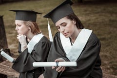 Två fundersamma kvinnlig som väntar på avläggande av examenpartiet arkivbild Två fundersamma kvinnlig som väntar på avläggande av examenpartiet arkivbild
