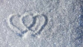 Två hjärtasymboler på snön, lott av snöflingor som flyger på vinden Två hjärtasymboler på snön, lott av snöflingor som flyger på vinden