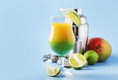Två-lager alkoholiserad coctail med mangofruktsaft, rom, likör, limefrukt och is, sommarblåttbakgrund, ställe för text arkivbild Två-lager alkoholiserad coctail med mangofruktsaft, rom, likör, limefrukt och is, sommarblåttbakgrund, ställe för text arkivbild