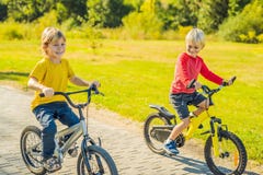 Två lyckliga pojkar som cyklar i, parkerar arkivfoton Två lyckliga pojkar som cyklar i, parkerar arkivfoton
