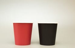 Två pappers- exponeringsglas för kaffeställning på en ljus bakgrund, svart och rött arkivfoton Två pappers- exponeringsglas för kaffeställning på en ljus bakgrund, svart och rött arkivfoton