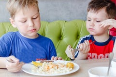 Två pojkar som äter pasta med en kotlett royaltyfria foton Två pojkar som äter pasta med en kotlett royaltyfria foton