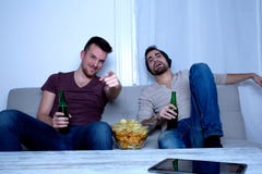 Två vänner som hemma håller ögonen på television royaltyfria bilder Två vänner som hemma håller ögonen på television royaltyfria bilder