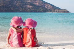 Twee Aziatische kleine kindmeisjes die en elkaar op het strand zitten koesteren dichtbij het mooie overzees in de zomervakantie stock fotografie Twee Aziatische kleine kindmeisjes die en elkaar op het strand zitten koesteren dichtbij het mooie overzees in de zomervakantie stock fotografie