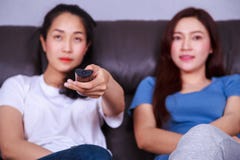 Twee beste vrienden die op TV met ver op bank thuis letten stock foto Twee beste vrienden die op TV met ver op bank thuis letten stock foto